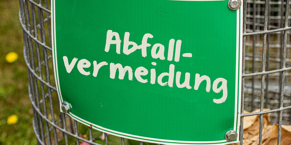 Bild: Gitter-Mülleimer mit weißem Schriftzug Abfallvermeidung auf grünem Schild