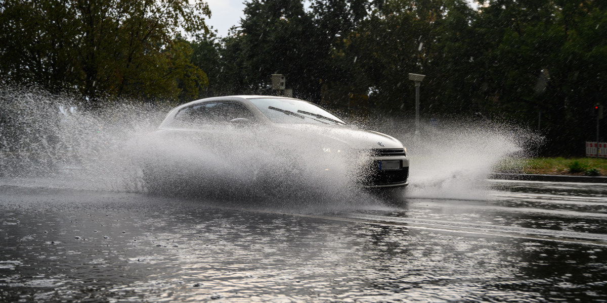Bild: Ein Auto fährt bei Starkregen durch eine sehr große Pfütze nach einem Starkregen.